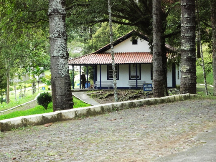 Casa branca de telhado vermelho, com varanda, entre árvores altas, onde nasceu Santos-Dumont e hoje funciona o Museu de Cabangu.