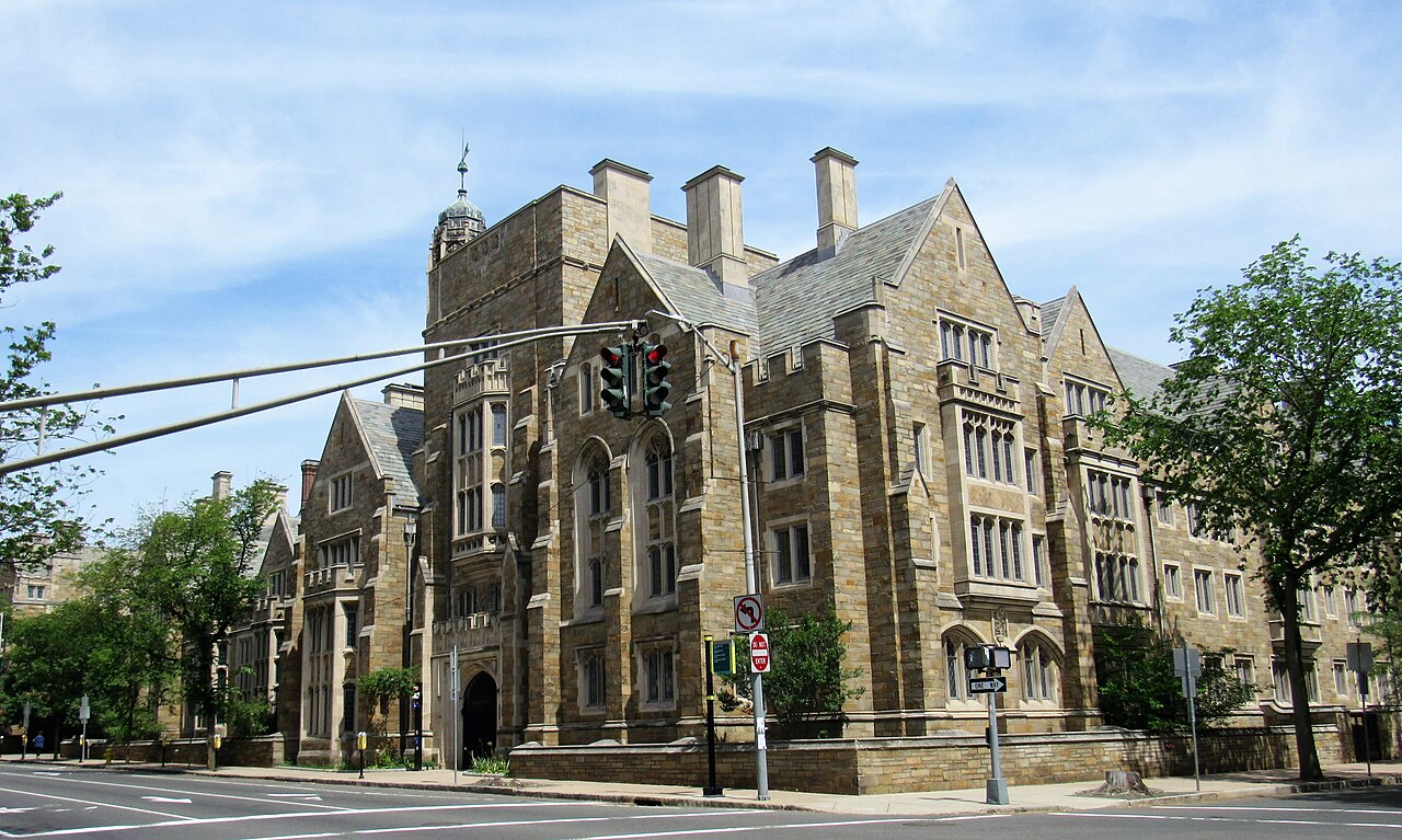 Fachada de pedra do Grace Hopper College, em estilo neogótico, numa esquina de New Haven, com semáforo e árvores em frente