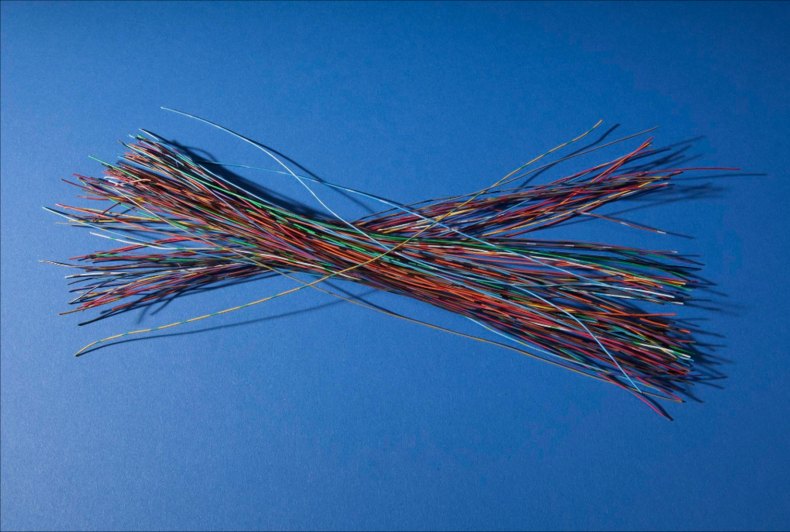 Feixe de fios elétricos de várias cores, cada um com cerca de 30 centímetros, cruzados sobre fundo azul: os nanossegundos de Hopper