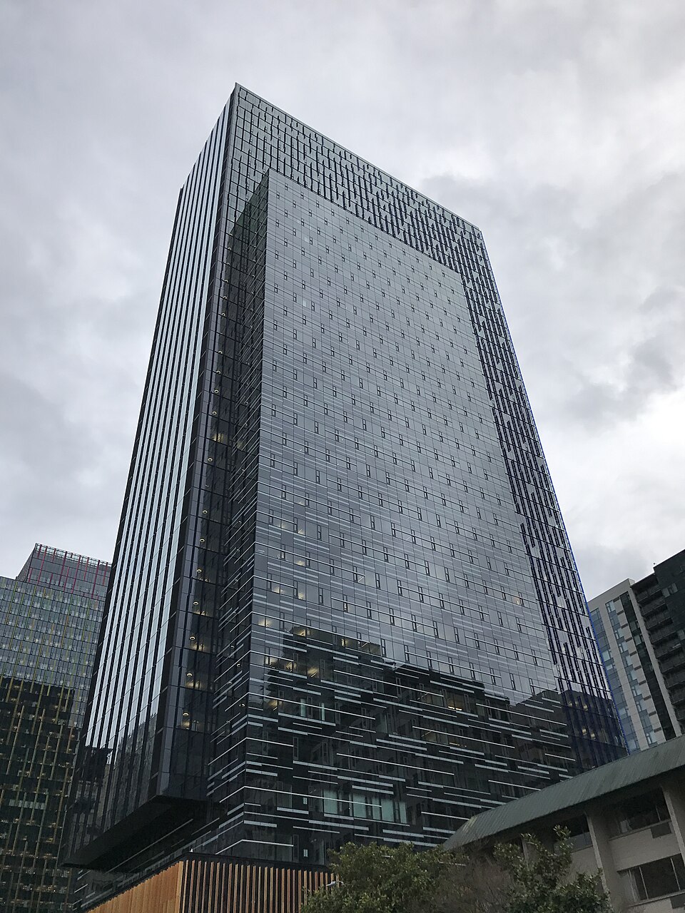 Torre de vidro e aço em Seattle, vista de baixo, com letreiros do prédio Day 1 da Amazon na fachada, sob céu claro.