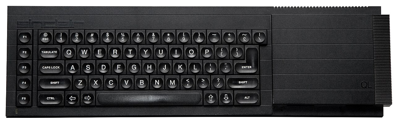 Teclado preto do Sinclair QL visto de cima, com teclas arredondadas, as teclas de função F1 a F5 à esquerda e a inscrição Sinclair no canto superior.