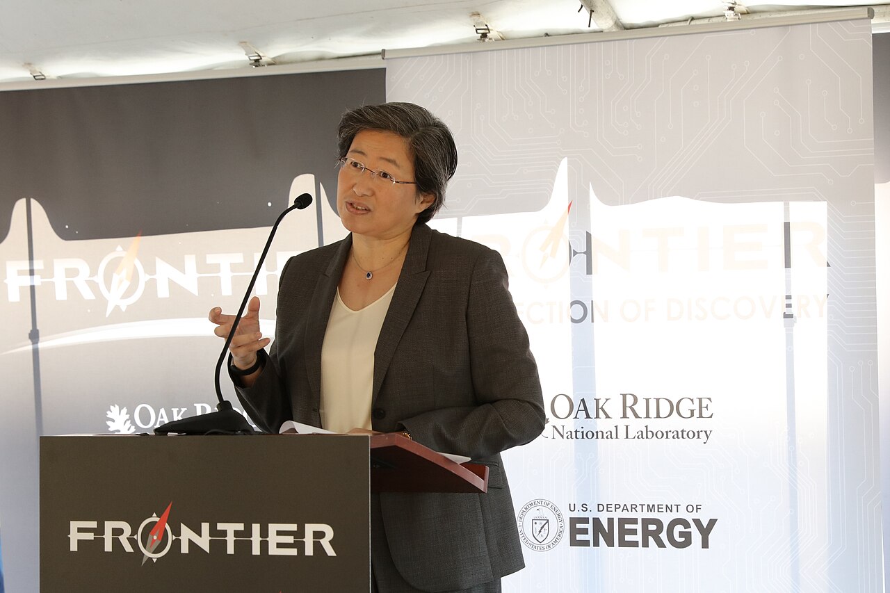 Lisa Su fala em um púlpito, diante de banners do projeto Frontier, do Laboratório Nacional de Oak Ridge e do Departamento de Energia dos EUA.