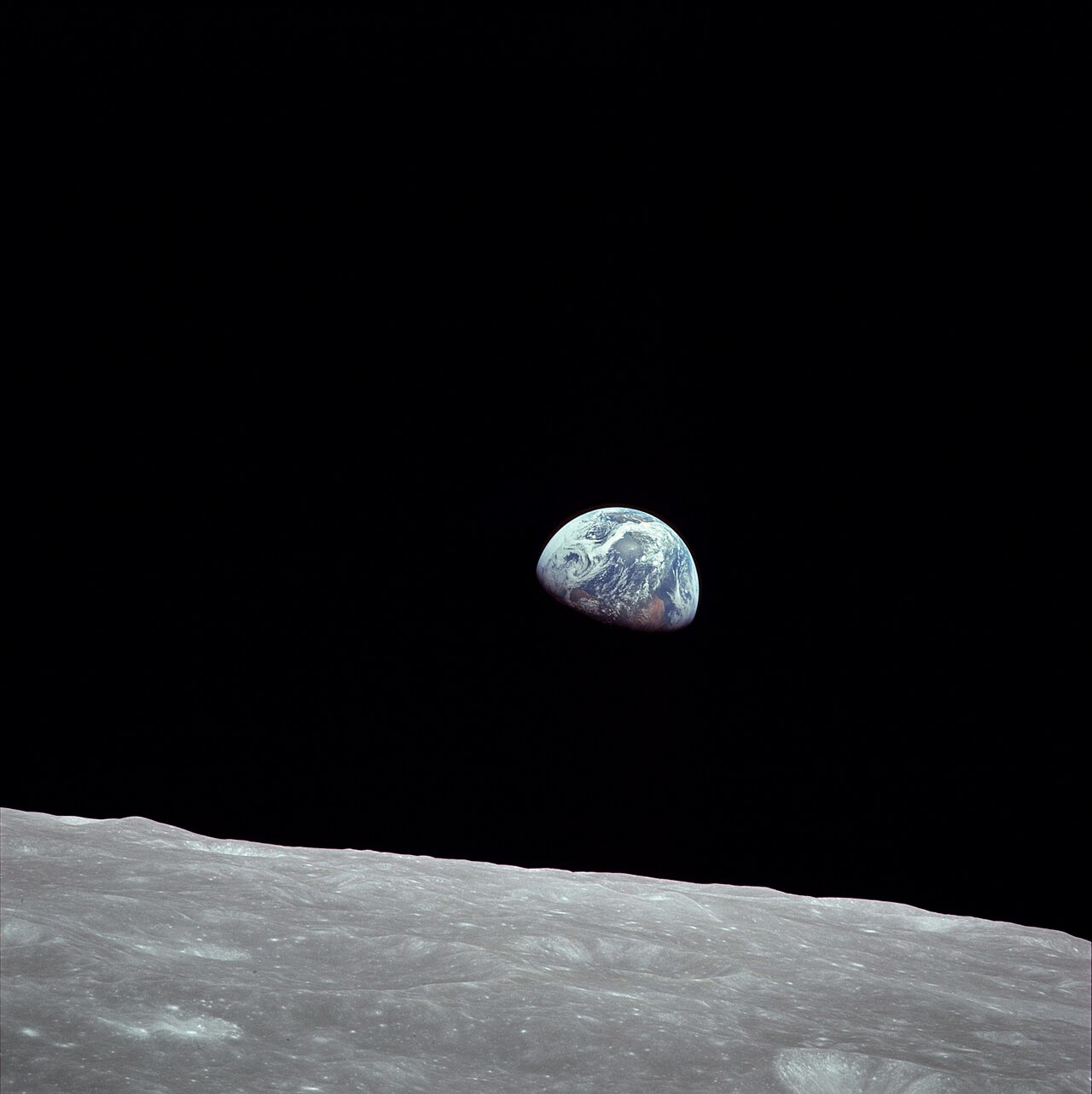 A Terra, azul e branca, sobe acima do horizonte cinzento e crivado de crateras da Lua, num céu preto, fotografada da órbita lunar.
