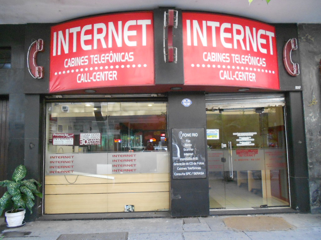 Fachada vermelha de um ponto de internet em Copacabana, com a palavra Internet em letras brancas, cabines telefônicas e call center.
